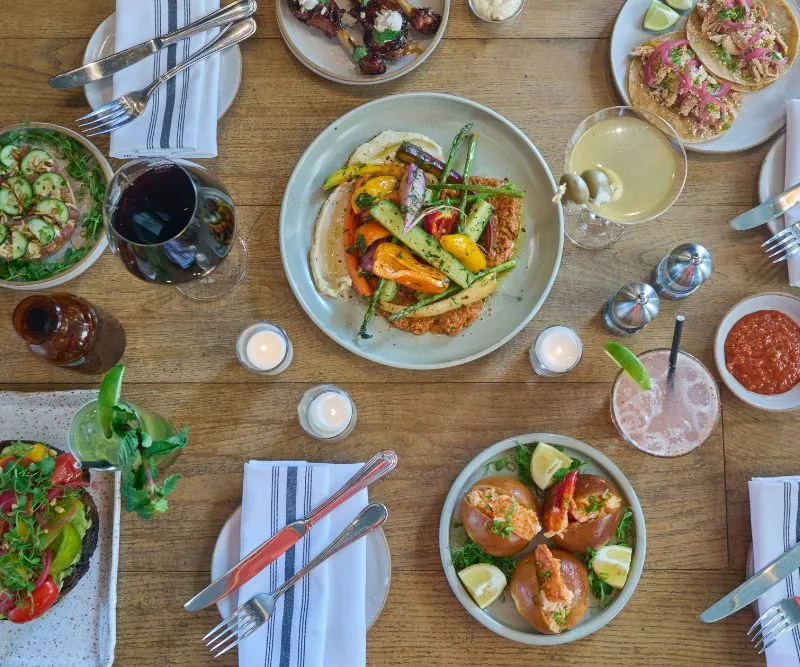 Appetizers and food on plates with candles, silverware and drinks