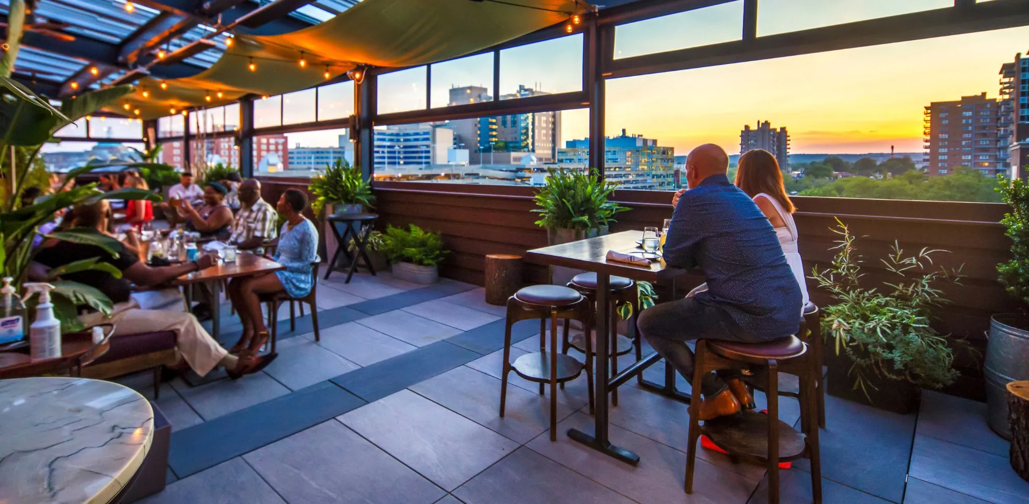 groups of people dining at multiple tables looking at a sunset at the High George